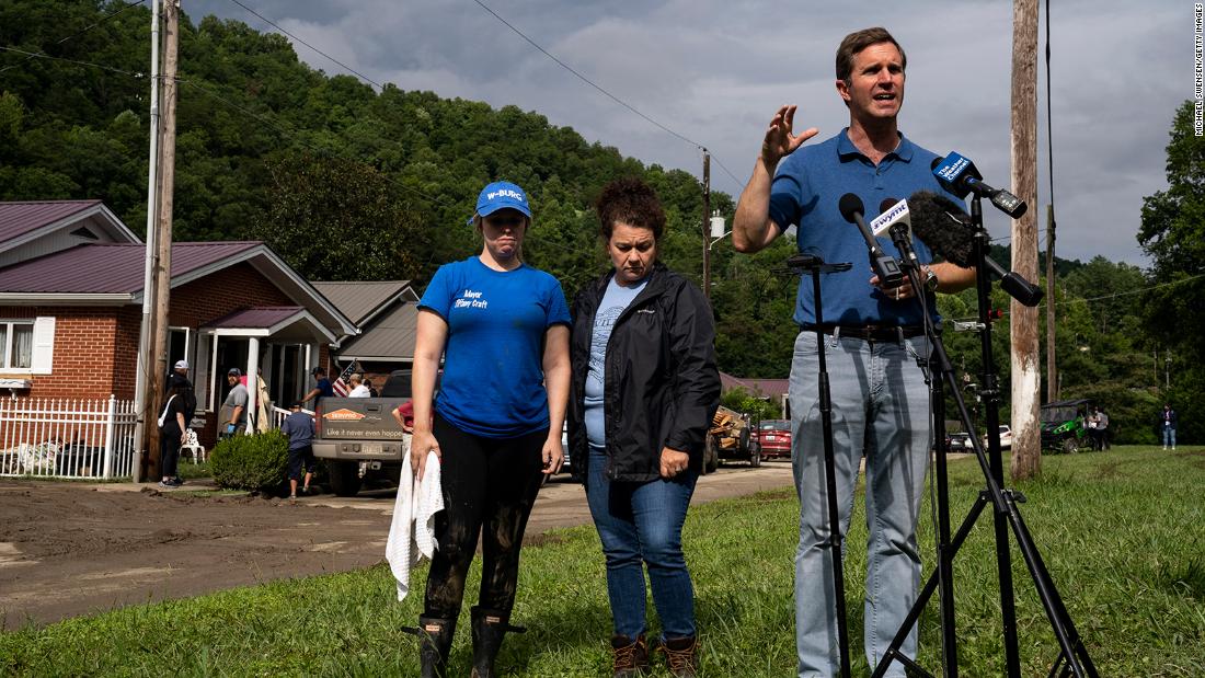 Kentucky Gov. Andy Beshear speaks to the media Sunday in Whitesburg, Kentucky.  Behind him are Whitesburg Mayor Tiffany Craft, sinistra, and state Rep. Angie Hatton.