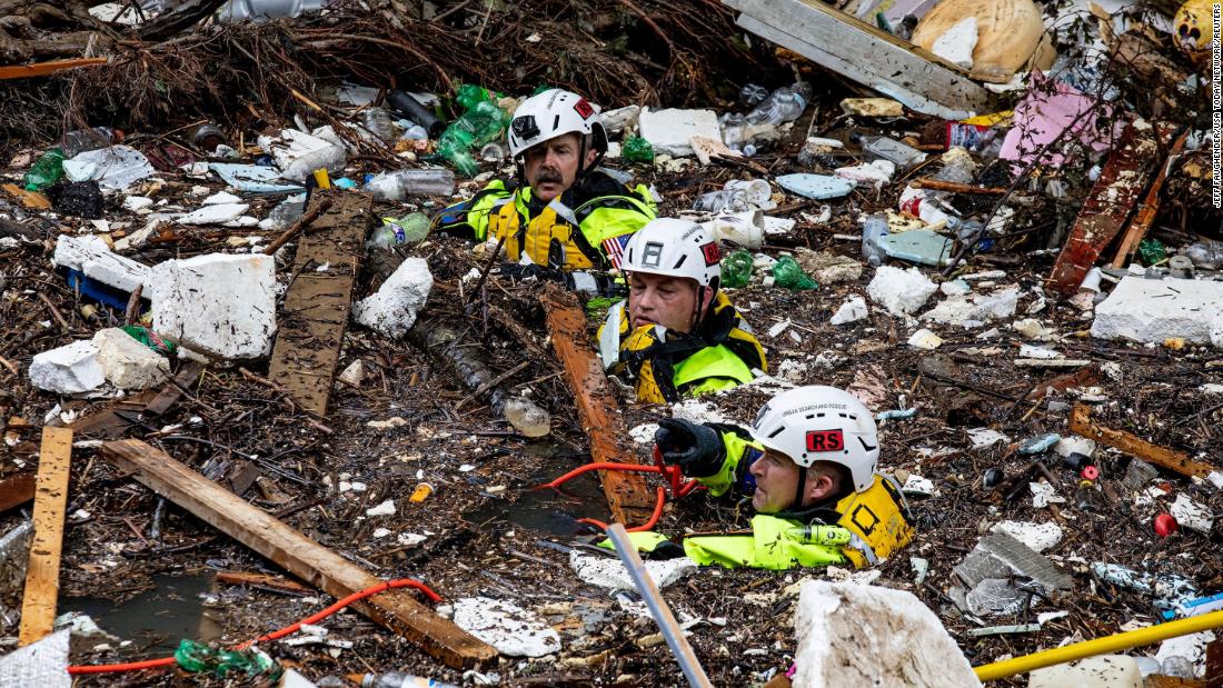 Members of a search-and-rescue team wade through the debris-filled Troublesome Creek after a search dog detected the scent of a potential victim in Perry County, 肯塔基州, 在星期天.