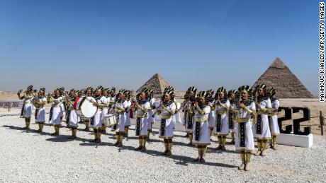 Marching band members dressed in ancient Egyptian clothing perform ahead of the Pyramids Airshow 2022 at the Giza Pyramids necropolis, on the southwestern outskirts of the Egyptian capital, El Cairo, en Agosto 3.  