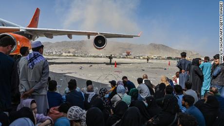 Afghan people wait to leave Kabul&#39;s airport on August 16, 2021, a day after the Taliban takeover. 