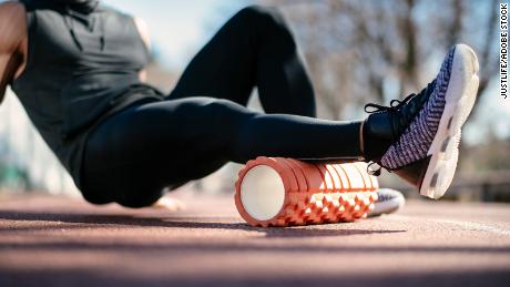 To help ease muscle knots, lie on a foam roller and gently roll your leg back and forth on it.