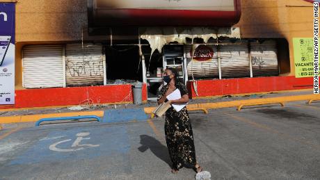A woman stands in front of a building that was burnt during violence that swept across parts of Ciudad Juarez.