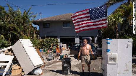 A man stands in front of a home damaged by storm surge in the wake of Hurricane Ian in Naples, Florida.