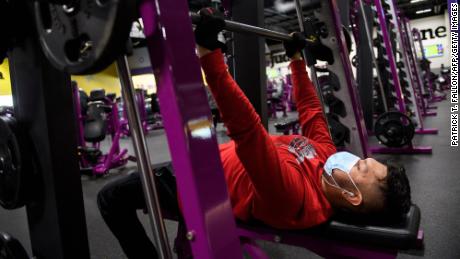 A customer wears a face mask as they lift weights while working out inside a Planet Fitness Inc. gym as the location reopens after being closed due to the Covid-19 pandemic, on March 16, 2021 in Inglewood, California.