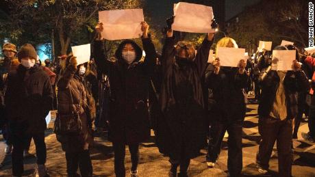 Protesters hold up blank papers and chant slogans as they march in protest in Beijing on Sunday night. 