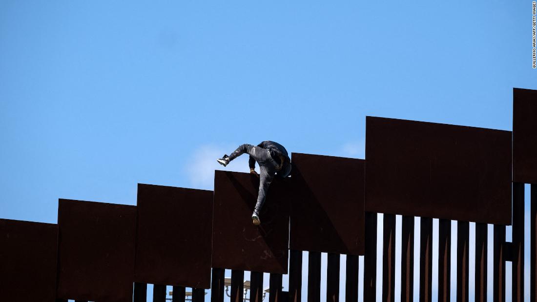 A migrant climbs over a border wall separating Tijuana from the United States after fetching groceries for other migrants who were waiting to be processed by US authorities on May 10.