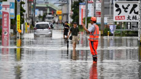 Residents manoeuver through a flooded street in the city of Kurume, Fukuoka prefecture, on July 10, 2023, after heavy rains hit wide areas of Kyushu island. One person died in a landslide and hundreds of thousands of people have been urged to evacuate their homes in southwestern Japan as forecasters on July 10 warned of the &quot;heaviest rain ever&quot; in the region. (Photo by Kazuhiro NOGI / AFP) (Photo by KAZUHIRO NOGI/AFP via Getty Images)