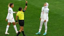Morocco's Nouhaila Benzina, the first player to wear a hijab at a World Cup, is shown a yellow card by referee Edina Alves Batista.