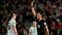 Referee Rebecca Welch shows a yellow card to US midfielder Rose Lavelle.