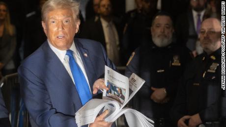 Former US President Donald Trump holds press clippings as he speaks to members of the media during his trial for allegedly covering up hush money payments linked to extramarital affairs, at Manhattan Criminal Court in New York City on April 18, 2024. Trump&#39;s criminal trial resumed Thursday with Judge Juan Merchan seeking to complete jury selection. Moving the US into uncharted waters, it is the first criminal trial of a former US president, one who is also battling to retake the White House in November. (Photo by JEENAH MOON / POOL / AFP) (Photo by JEENAH MOON/POOL/AFP via Getty Images)