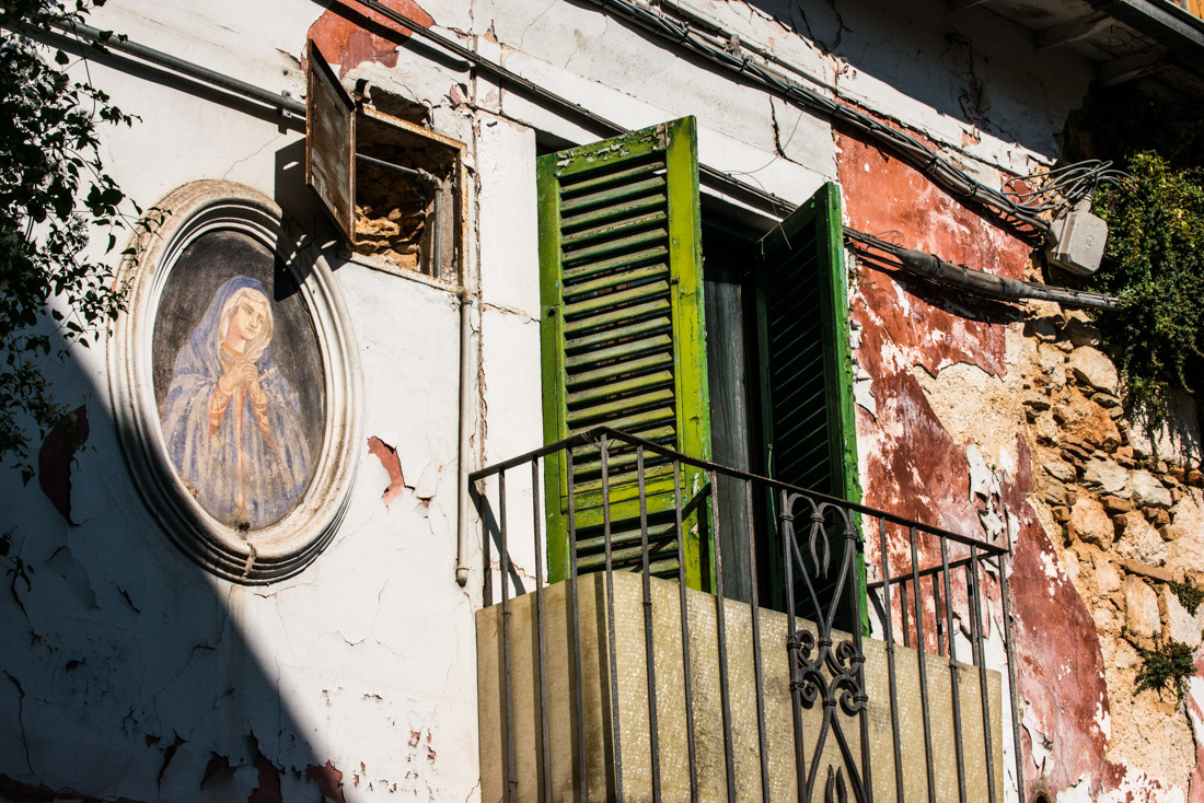 A religious fresco adorns a damaged house.