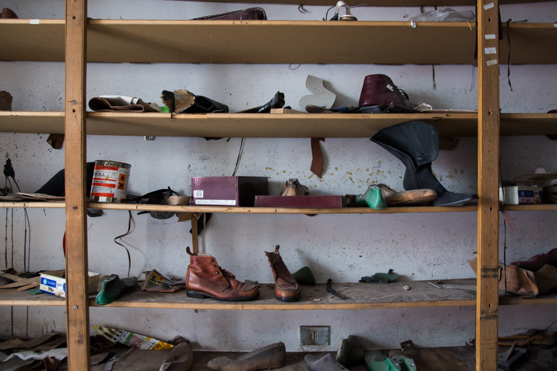 Shoes lie scattered across shelving in a former shop.