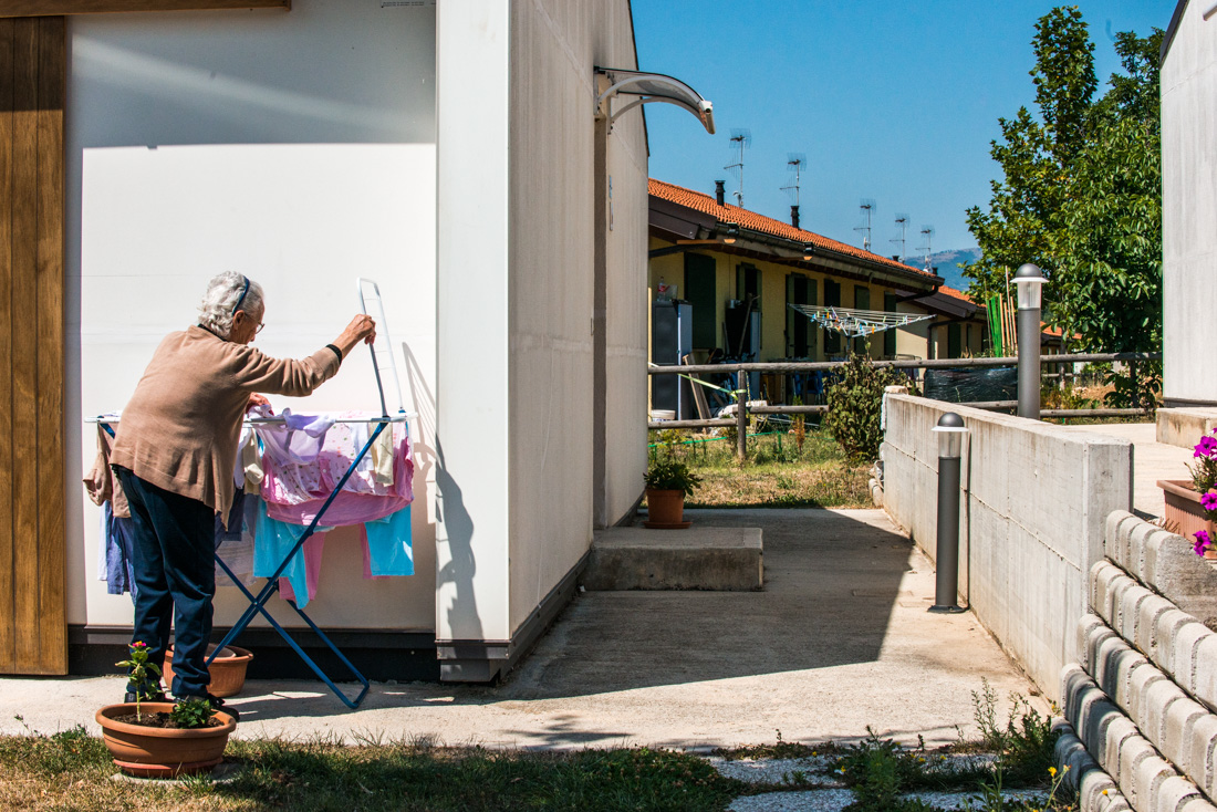 An elderly woman hangs laundry to dry outside the pre-fabricated houses built by volunteers in the months following the earthquake.