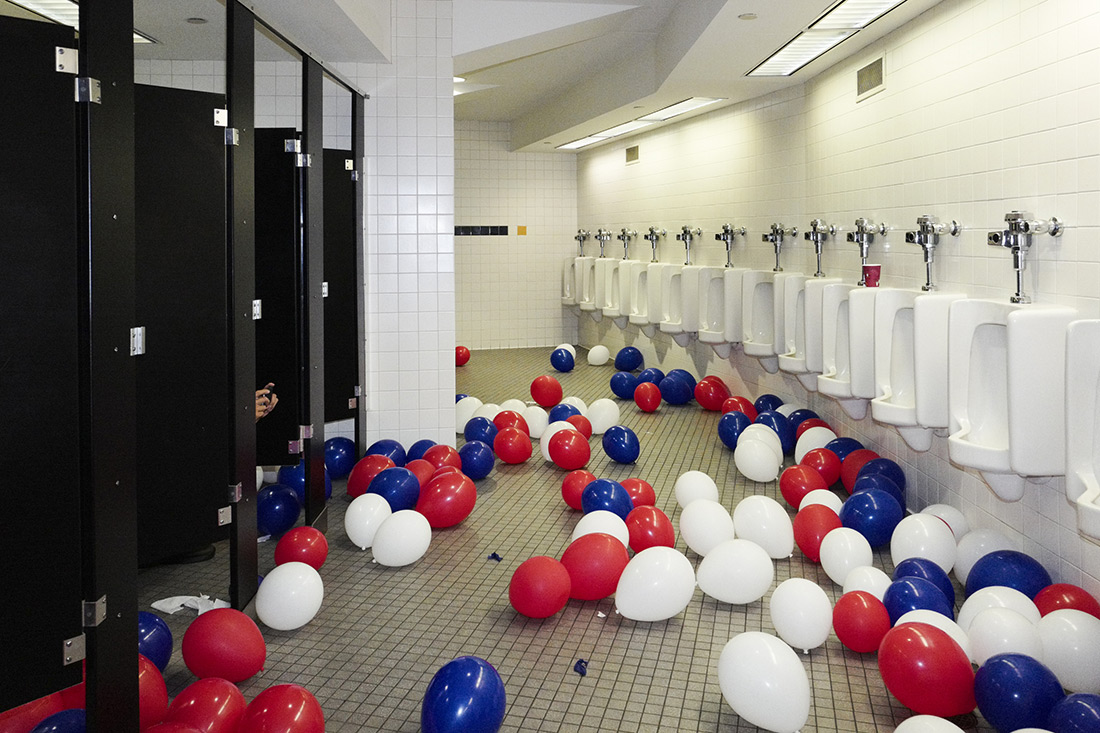 A man in a bathroom stall photographs balloons at the end of the Republican convention.