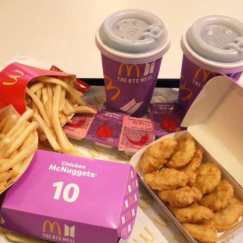 Mcdonalds meal on a tray with chips, chicken nuggets and drinks in purple packaging branded with BTS.