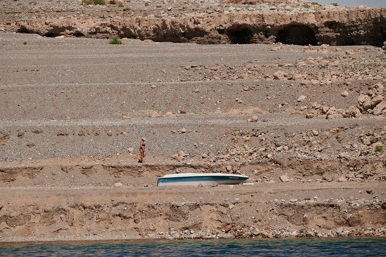 A boat sits on a sandy shelf that is exposed by receding water.