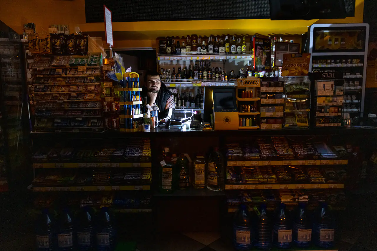 A gas station employee in Kyiv stands inside a darkened shop during a power outage in October. Amid rolling power outages in the capital, some gas stations tried to rotate their generators in order to maintain electricity.