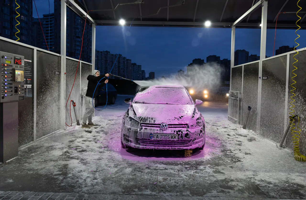 A man washes his car in freezing temperatures as the neighborhood behind him on Kyiv’s left bank goes dark.