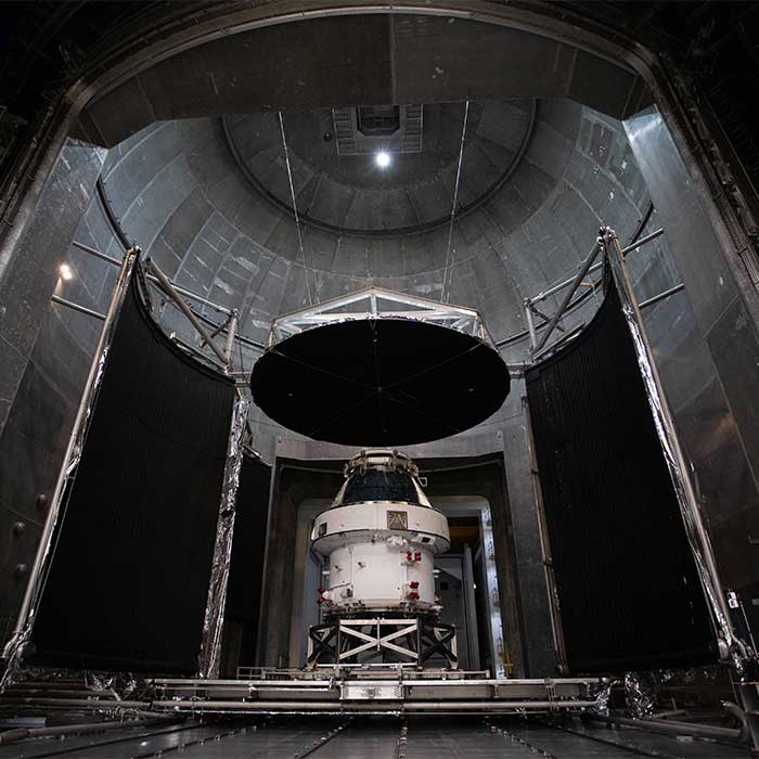 The white Orion spacecraft is shown inside a huge metal structure.