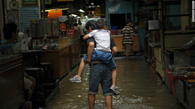 A man carries a boy on his back at a flooded market in a low-lying area of downtown Bangkok on 4 October.