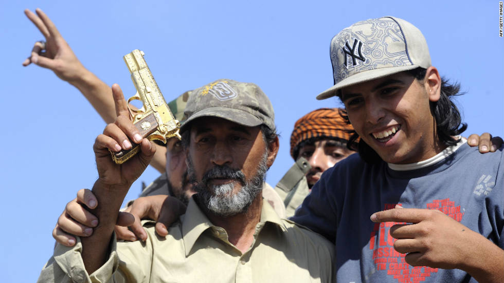 NTC fighters hold what they say is the ousted Libyan leader&#39;s gold-plated gun Thursday.
