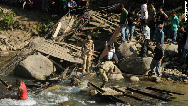 Indian villagers and rescuers gather at the scene of a bridge that collapsed on Saturday.