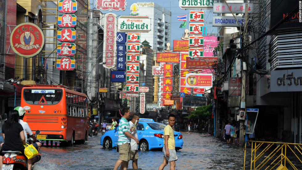 Thai residents walk in floodwaters along a street in the Chinatown section of Bangkok.