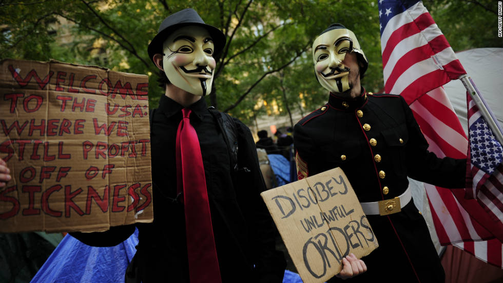 Masked Occupy Wall Street supporters hold signs at Zuccotti Park in New York on October 30. 