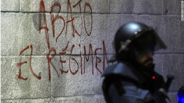 Graffiti says &quot;Down with the regime&quot; on Spain&#39;s parliament building near a riot officer during a protest before elections this month.