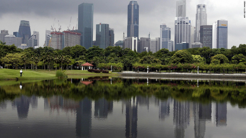A crowded row of skyscrapers are reflected on a man-made lake while a dark cloud hovers in Singapore. Matthew Kahn, economics professor at the UCLA&#39;s Environment Institute, says that this type of high-rise, high-density urban living will be the norm in years to come, as cities adapt to migrants escaping their climate-ravaged homes.