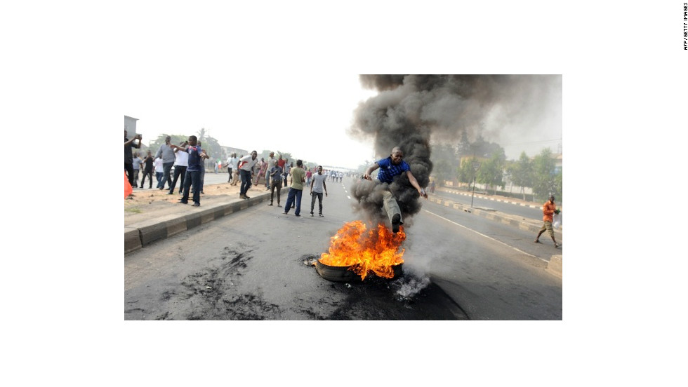 A boy jumping over a burning tyre on a street in Nigeria where protests against the removal of fuel subsidy have raged since 3 January. 