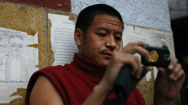 A monk in New Delhi in this file picture stands next to an image of a Tibetan monk that self-immolated in Tibet.