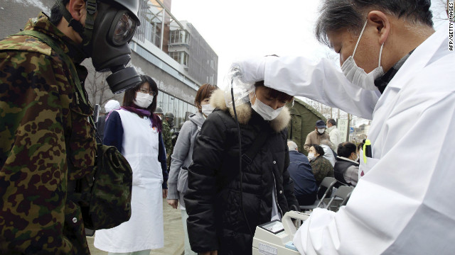 A doctor checks the level of radiation on a woman at a treatment centre in Nihonmatsu city on March 13, 2011. 