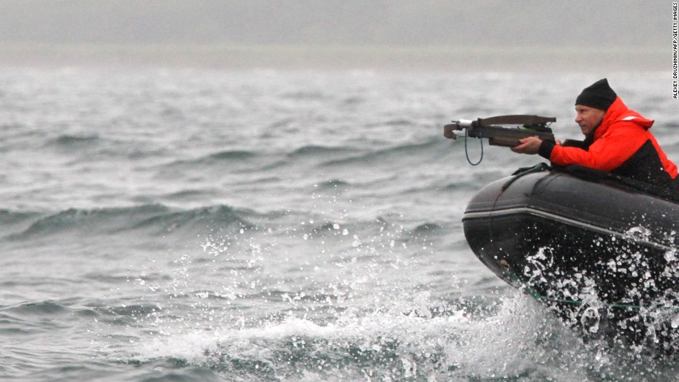 The Russian president aims at a whale with an arbalest (crossbow) to take a piece of its skin for analysis at Olga Bay on August 25, 2010.