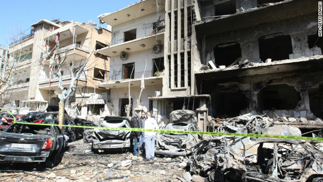Syrian security officers inspect the scene at a destroyed building following twin bomb attacks in Damascus on Saturday.