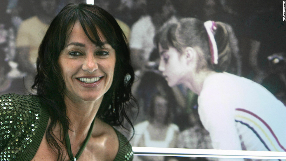 Comaneci, who won five gold medals in two Olympic appearances, stands next to a picture of herself competing at Montreal. 