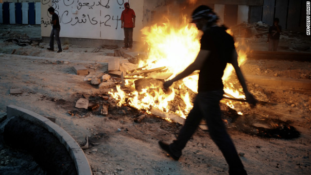 A Bahraini Shiite Muslim walks past a fire as protestors clashed with riot police on March 31, 2012.
