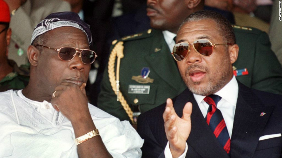 Liberian President Charles Taylor, right, chats to Nigerian counterpart Olusegun Obasanjo during a symbolic bonfire to destroy weapons in Monrovia in July 1999.