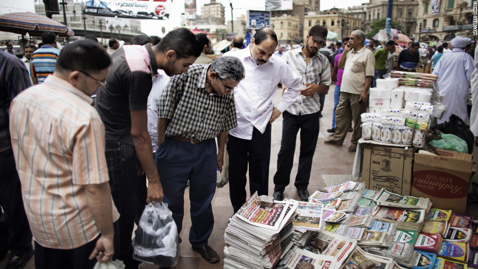 Egyptians read the front page of newspapers for sale outside of Al-Fatah Mosque in Cairo on Friday, May 25.