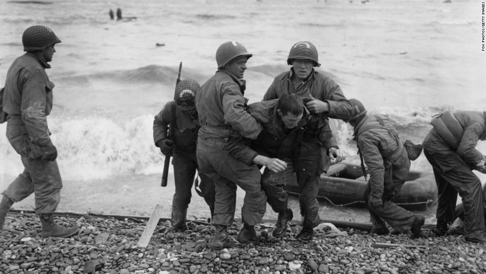 American troops help their injured comrades after their landing craft was fired upon. Allied forces secured the beaches at a cost of about 10,000 casualties.