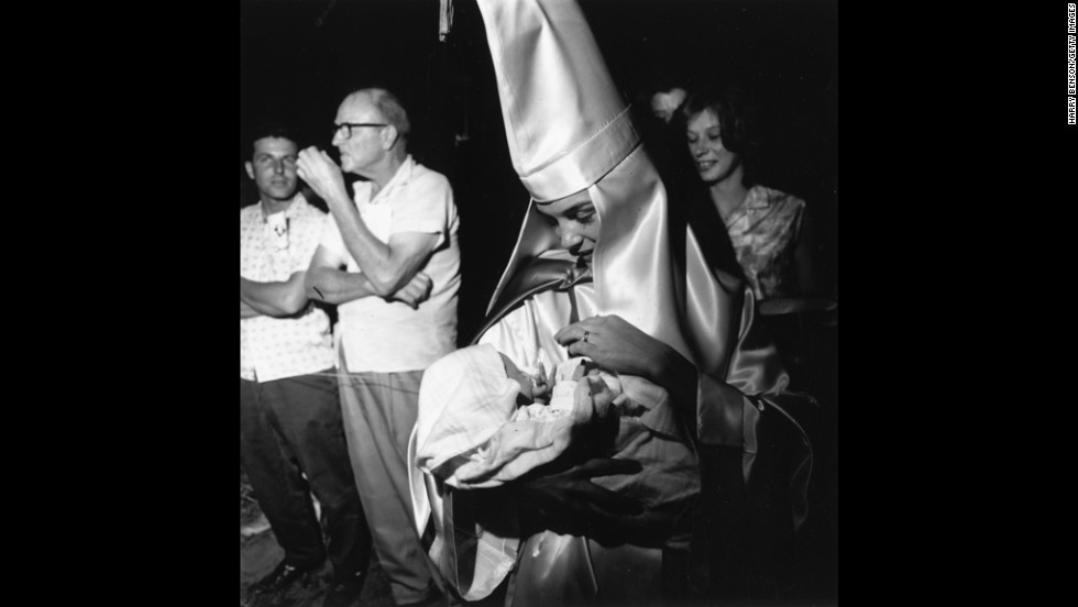 A woman dressed in Ku Klux Klan regalia holds her baby at a KKK meeting in Beaufort, South Carolina, in 1965.