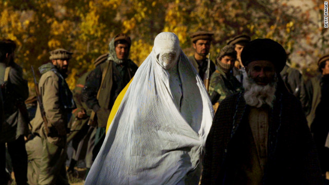 A woman wearing a traditional burqa flees the village of Khanabad U.S. warplanes drop bombs on Taliban positions in 2001.