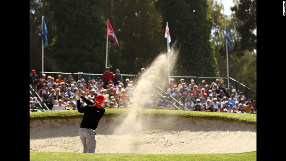 Hunter Mahan of the United States plays a bunker shot on the 17th hole during the first round.
