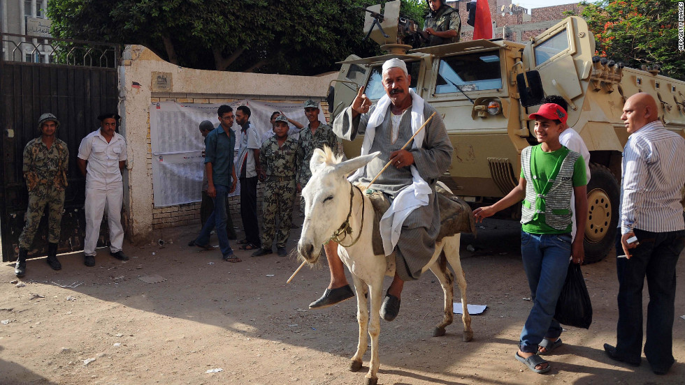 An Egyptian man on his donkey shows his ink-stained finger after casting his ballot.