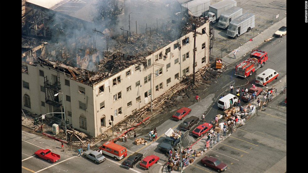 People line the sidewalk across from a burned out apartment building that was destroyed in the violence. More than 1,100 buildings were destroyed or damaged during the riots.