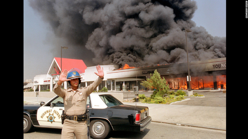 A California Highway Patrol officer directs traffic around a shopping center engulfed in flames on April 30.