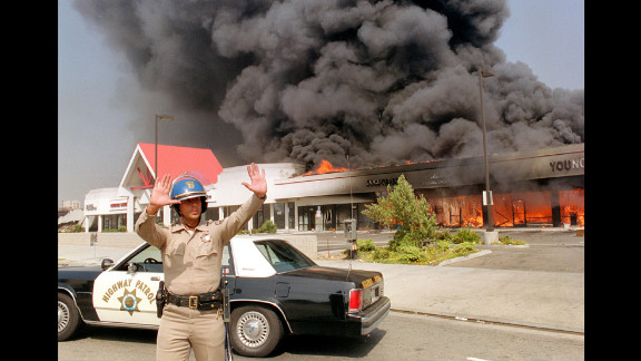 A California Highway Patrol officer directs traffic around a shopping center engulfed in flames on April 30.