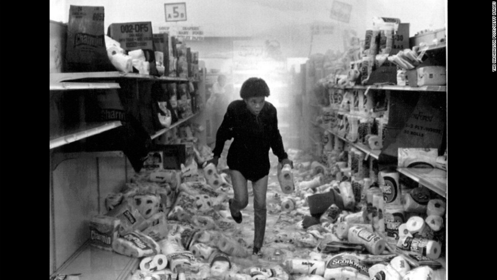 A woman runs out of a store that has been heavily looted as the overhead sprinkler system is triggered on May 1. More than 700 retail stores were damaged during the riots.