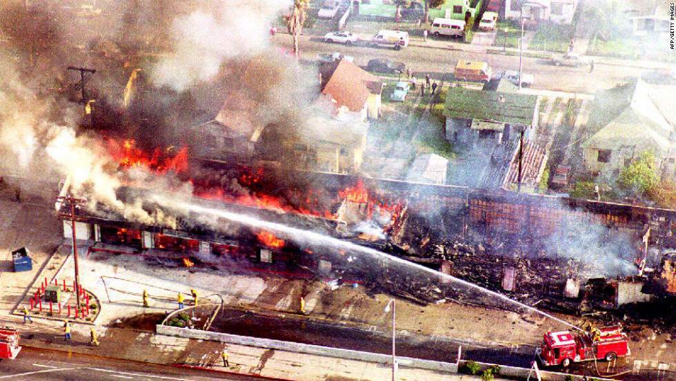 Firefighters spray water on a burning building in south Los Angeles on April 30, 1992, a day after rioting broke out over  the acquittal of four white police officers charged with assault and the use of excessive force on Rodney King.