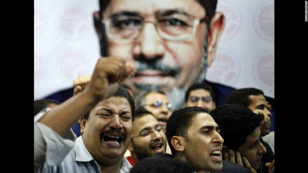 Morsi suppporters celebrate in front of a picture of him at his campaign headquarters in Cairo on June 24.